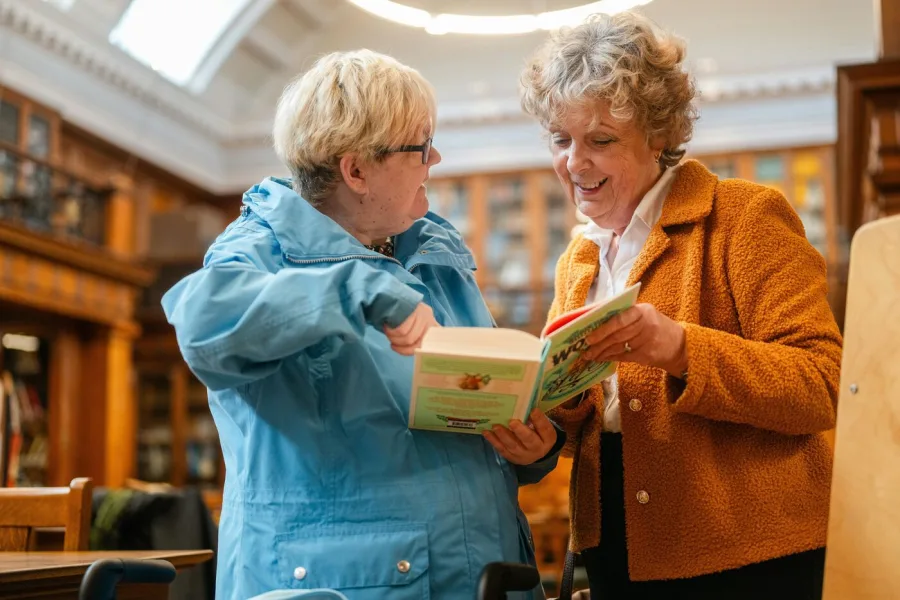 Support worker and participant reading together at a library — NDIS social and community participation in Perth