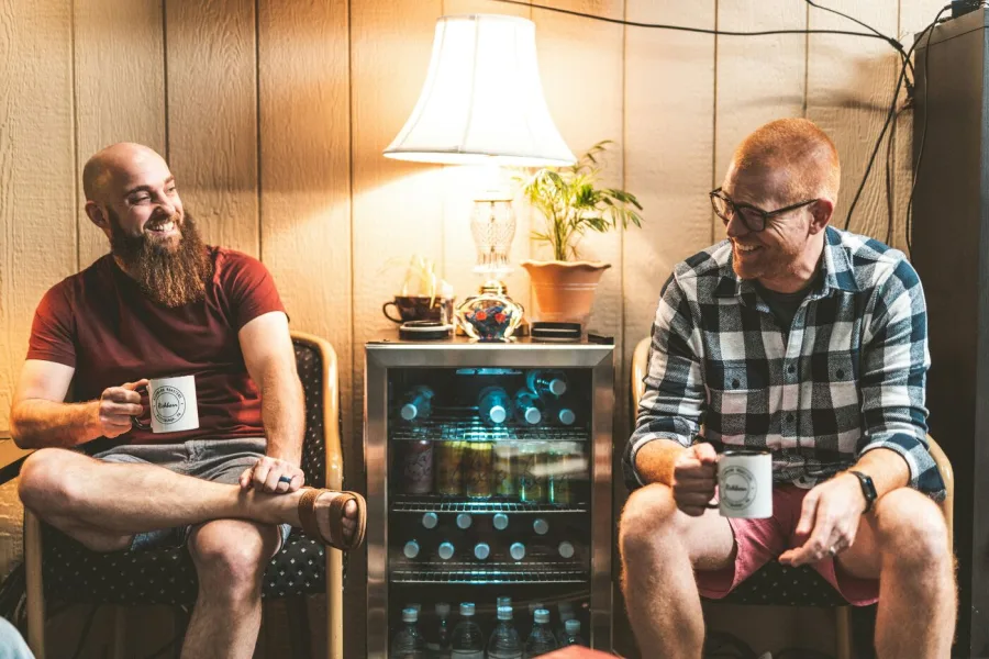 Two men talking over coffee in a relaxed setting — NDIS psychosocial recovery coaching in Perth